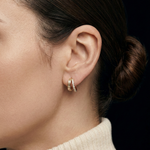 Close-up of a model wearing the gold Modernist Double Diamond Hoop earrings with baguette and brilliant-cut diamonds.