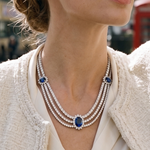 A model wears the Lark & Berry Kensington Necklace, a multi-strand diamond necklace with three large blue sapphires, over a cream jacket.
